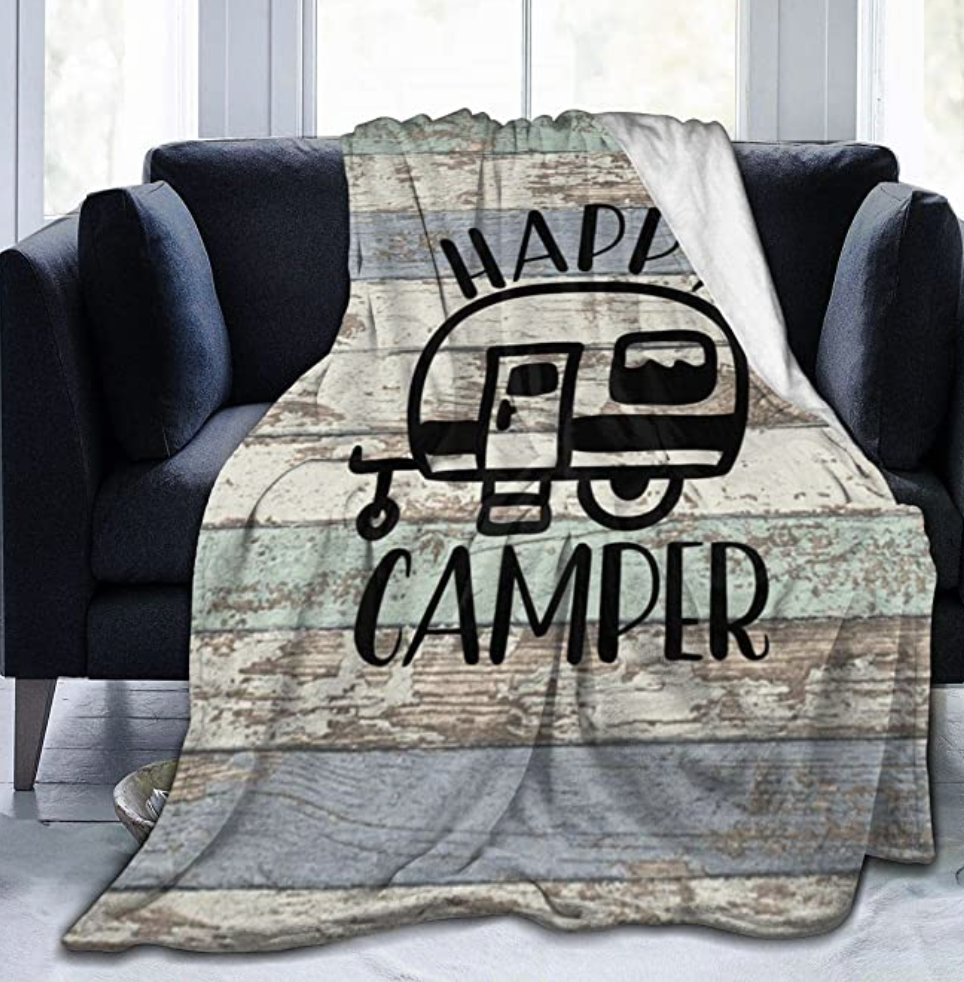 A soft warm throw blanket gift idea for RV owners that says "Happy Camper"