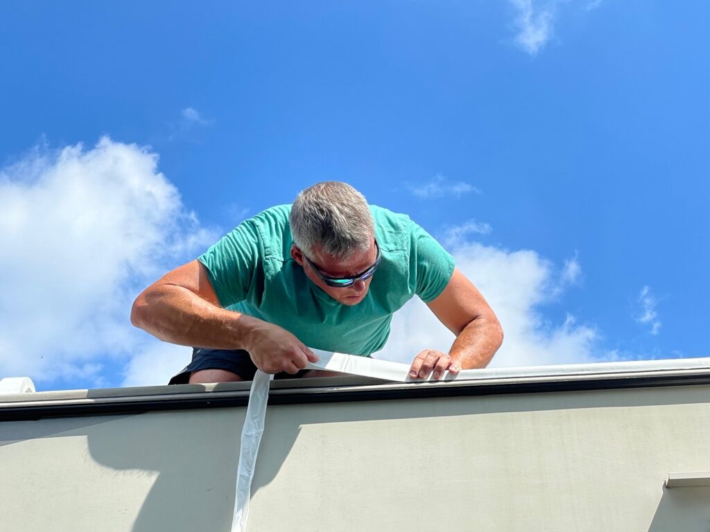 Close up of man adding sealing tape along edge of roof